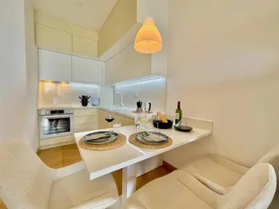 a white kitchen with a white table and chairs at Feel the Spirit Apartment in Budva