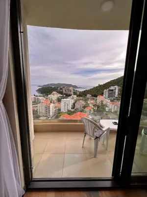 a chair on a balcony with a view of a city at Sea & Sky Apartments in Budva