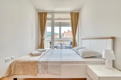 a white bedroom with a large bed and a window at Sigma apartment in Budva