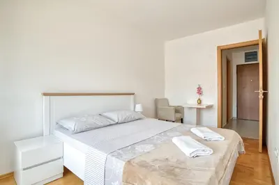 a white bedroom with a bed with two towels on it at Sigma apartment in Budva