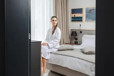 a woman in a robe sitting on a bed at Boutique Hotel Shell in Budva