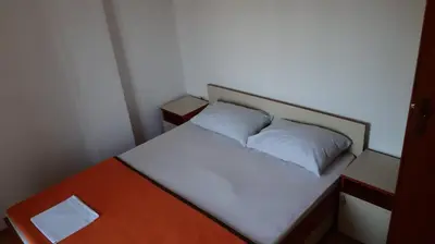 a small bedroom with a bed and a table at Apartman Petar in Budva