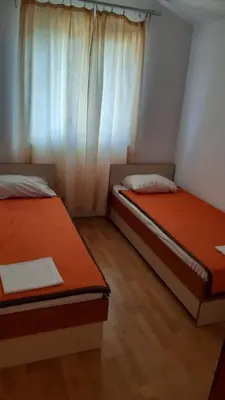 two beds in a small room with a window at Apartman Petar in Budva