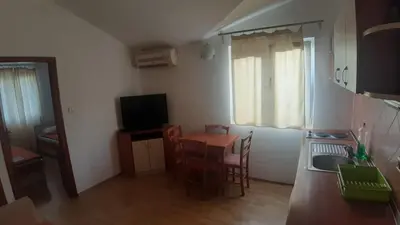 a small room with a table and a kitchen with a sink at Apartman Petar in Budva