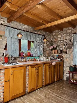 a kitchen with wooden cabinets and a stone wall at Village house Velimirović in Danilovgrad