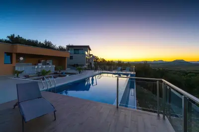 a view of a house with a swimming pool at sunset at Solana's View - Ferienhäuser in ruhiger Lage, mit einer einzigartigen Aussicht, Infinity Pool, Free Parking und Wlan in Ulcinj