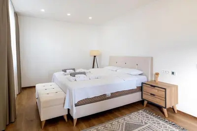 a white bedroom with a large bed and a table at Villa Cape Montenegro on Cliffside in Kotor
