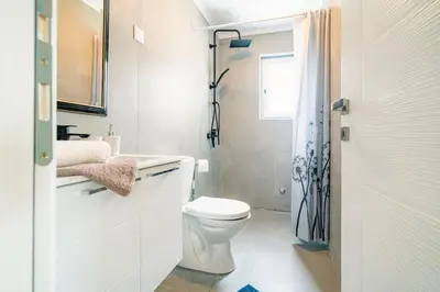 a white bathroom with a toilet and a sink at Pool & River House - Lazara in Danilovgrad