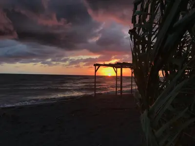 a sunset on the beach with a pergola at The sun is happiness in Ulcinj