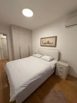 a bedroom with a large white bed and a nightstand at White Homes 45 • Central Point in Podgorica