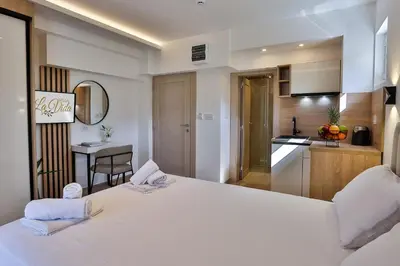 a bedroom with a large white bed and a kitchen at Villa La Vida in Budva