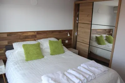 a bedroom with a large white bed with green pillows at Carefree Apartments in Ulcinj