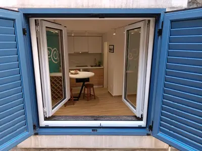 a window view of a kitchen from a house with blue shutters at Studio Apartment Danka Old Town Budva in Budva