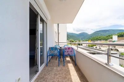two chairs sitting on a balcony looking out at the mountains at MAS Apartments in Kotor