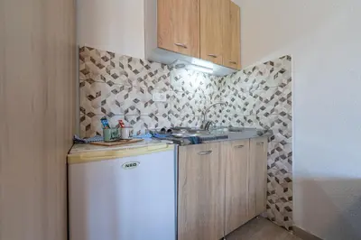 a small kitchen with a white refrigerator and wooden cabinets at MAS Apartments in Kotor