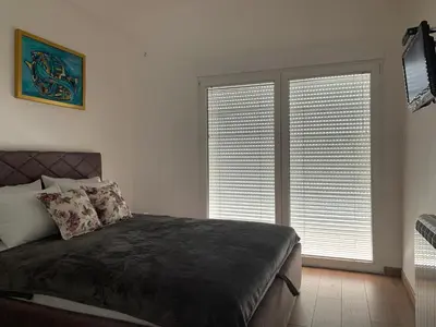 a bedroom with a bed and two large windows at D&D apartments in Sutomore