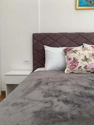 a bed with a headboard and pillows next to a table at D&D apartments in Sutomore