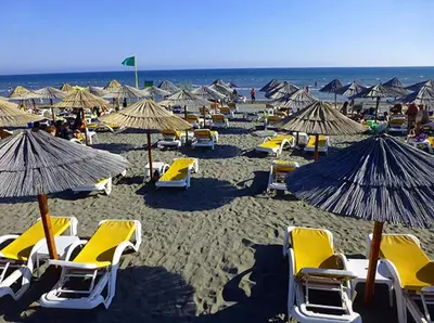 a bunch of chairs and umbrellas on a beach at Garden Apartments in Ulcinj