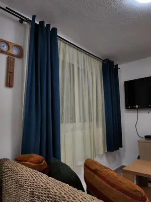 a living room with blue curtains and a tv at Smurf's house in Budva