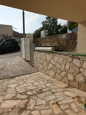 a stone retaining wall next to a building with a stone wall at Smurf's house in Budva