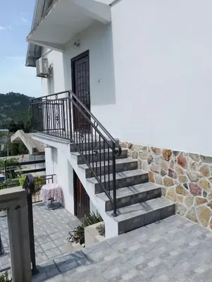 a staircase leading to a house with a stone wall at Apartman Jovanovic in Sutomore