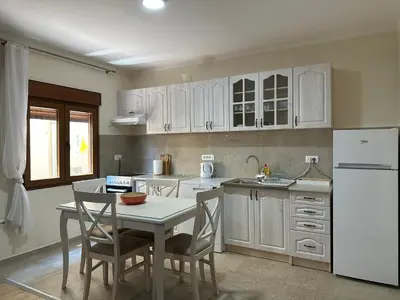 a kitchen with white cabinets and a table with chairs at Tara Two Bedroom Apartment - Budva in Budva