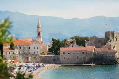 a group of people on a beach next to a castle at Tara Two Bedroom Apartment - Budva in Budva