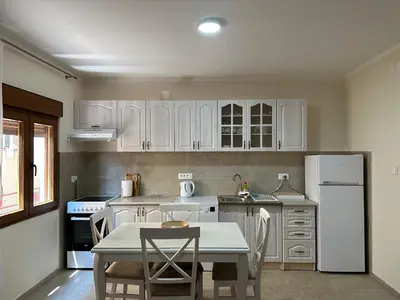 a kitchen with white cabinets and a table and chairs at Tara Two Bedroom Apartment - Budva in Budva