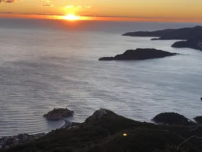 a sunset over the ocean with islands in the water at Apartman Bonaca in Pržno