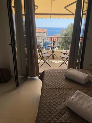 a bedroom with a bed and a balcony with a table and chairs at Apartman Bonaca in Pržno