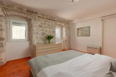 a bedroom with a large bed and a stone wall at M&M Bay Haven in Kotor