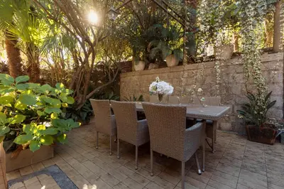 a patio with a table and chairs in a garden at M&M Bay Haven in Kotor