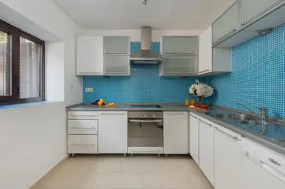 a kitchen with white cabinets and blue tiles at M&M Bay Haven in Kotor