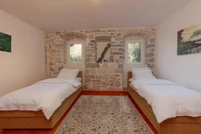 two beds in a room with a stone wall at M&M Bay Haven in Kotor