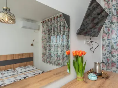 a room with a bed and a vase of orange tulips at Apartments Nona in Ulcinj