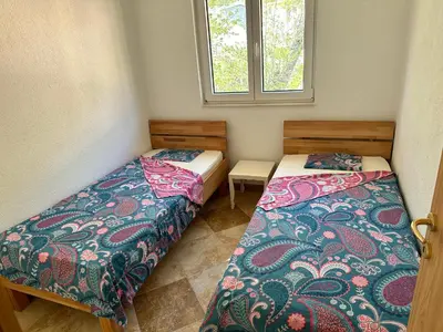 two beds in a small room with a window at Best View Apartment in Sutomore