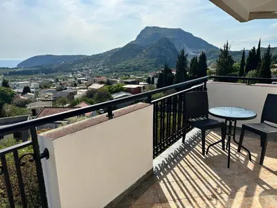 a balcony with a table and chairs and a mountain at Best View Apartment in Sutomore