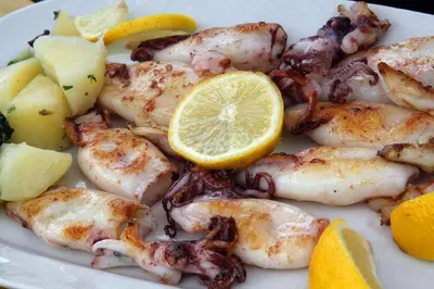 a plate of shrimp with a lemon and other foods at Vila Elkom, Apartment 5 in Ulcinj