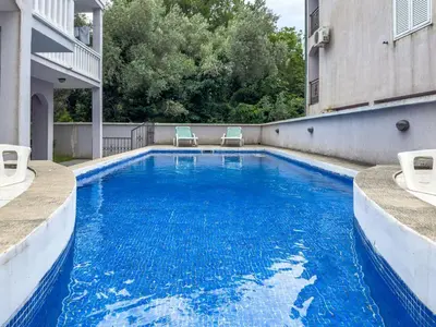 a swimming pool with two chairs sitting next to a building at Appartment Frick in Sutomore