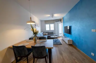 a dining room and living room with a blue wall at Apart Kraft in Podgorica