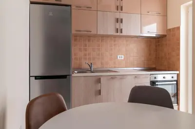 a kitchen with a table with chairs and a refrigerator at Apartment Xenia in Petrovac na Moru