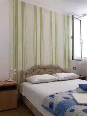 a bedroom with a bed with green and white stripes at Ćetković in Petrovac na Moru