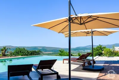 a swimming pool with two chairs and an umbrella at Golden Suit Tivat Heights-Pool & Seaview C1 in Kavač