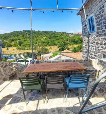 a wooden table and chairs on a patio with a view at Skalina House in Tivat