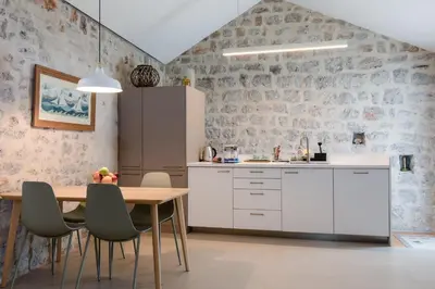 a kitchen with white cabinets and a table and chairs at Skalina House in Tivat
