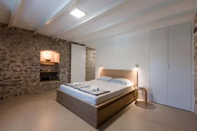 a bedroom with a bed and a brick wall at Skalina House in Tivat