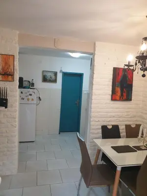 a kitchen with a table and a blue door at Apartmani Ema in Sutomore