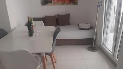 a small room with a bed and a table and chairs at Apartmani Ema in Sutomore
