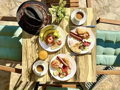 a table with plates of food and cups of coffee at Akhdar Apartments in Utjeha