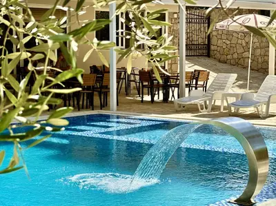 a swimming pool with a fountain in the middle at Akhdar Apartments in Utjeha